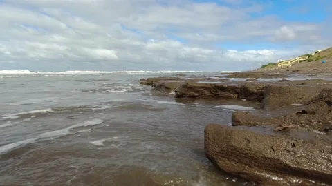 Small waves of the sea hitting the rocks on the shore of a beach Stock Footage 171348394