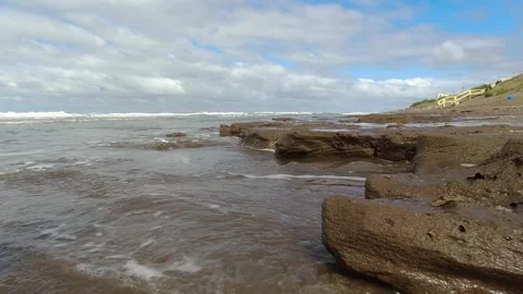 Small waves of the sea hitting the rocks on the shore of a beach Stock Footage 252399578