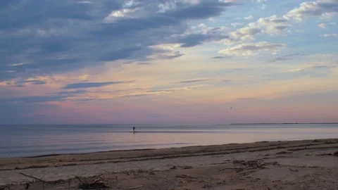 Small waves on the sea at sunset and a man on a surfboard Stock Footage 196557646