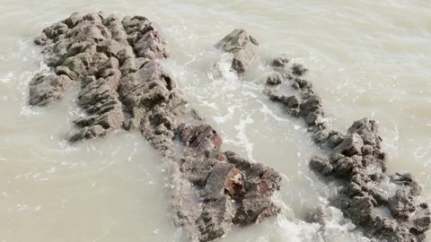 Small waves slowly roll over the rocks. foaming between rocks in the south .. Video stock 250812223