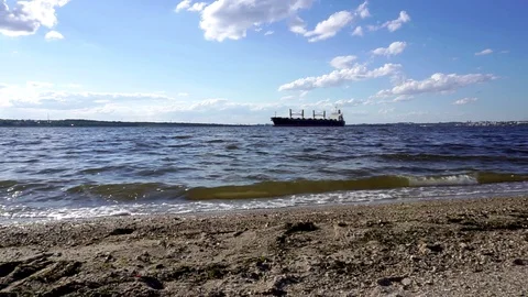 Small waves splashing calmly on sand shore beach as large cargo freight Stock Footage 95224469