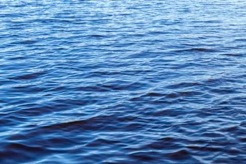 Small waves on the surface of the lake. Beautiful texture of blue water. On a Stock Photos