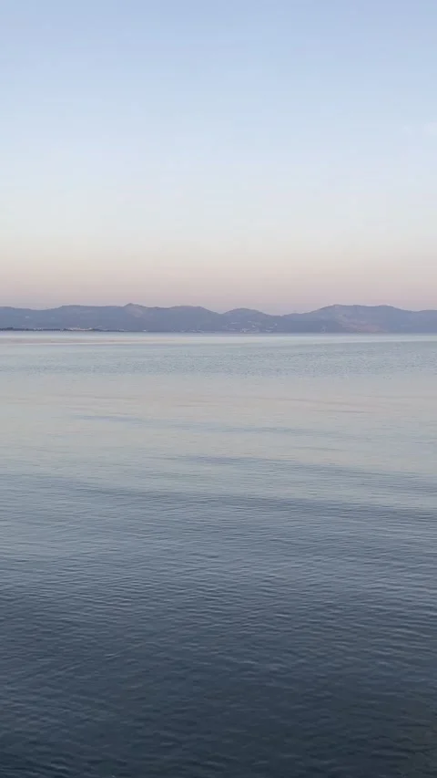 Small waves on the surface of the sea at sunset with mountains in the background Stock Footage 278361959