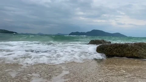 Small waves wash over the rocks lying on the shore. Stock Footage 236693328