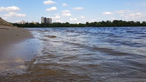 Small waves washing up a river shore with light brown sand in a sunny day. Stock Footage 112028897