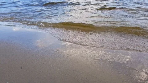 Small waves washing up a river shore with light brown sand in a sunny day. Stock Footage 112029075