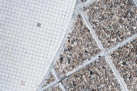 Small white and dirty squared ceramic tiles and old brown pebble stone floor. Stock Photos