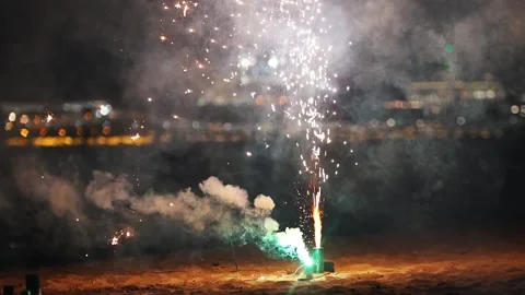 Small white and green firework burning and exploding on the beach and produces Stock Footage 133677080