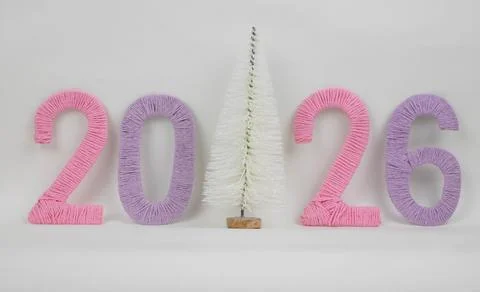 A small white artificial Christmas tree and the numbers 2026 made of pink and Stock Photos