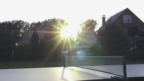 A small white ball for table tennis flies at the net against a beautiful sunset Stock Footage 81179575