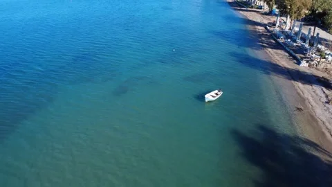 Small white boat anchored in shallow turquoise bay near island beach Stock Footage 343995783