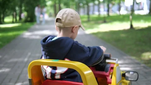 A small white boy of about 4-5 years old drives and controls a toy car Stock Footage 311826570
