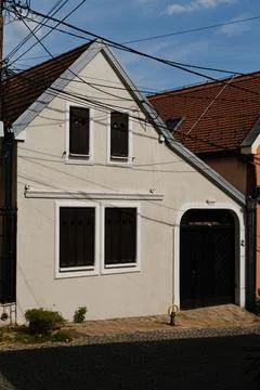 Small white building with closed brown shutters and sloped red roof in Zemu.. Stock-Fotos