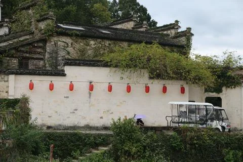 A small white bus is parked in front of the wall, and red lanterns hang on it Stock Photos