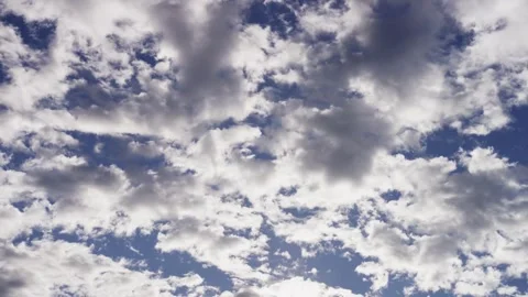Small white clouds move across a bright blue sky Stock Footage 329757625