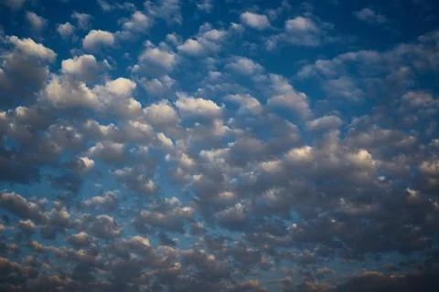 Small white clouds in the sky in the sunlight of the setting sun Foto stock