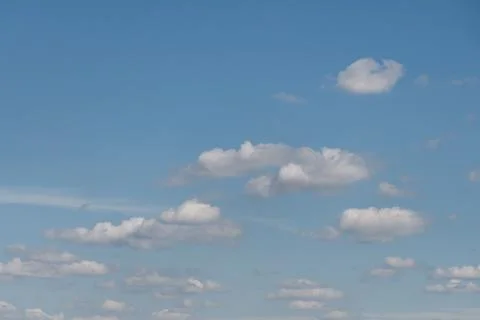Small white cumulus cloud formations across blue sky Stock Photos