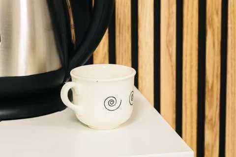 Small white cup of coffee on the edge of the table. Stock Photos