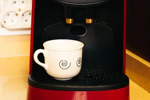 Small white cup of coffee inside the coffee maker Stock Photos