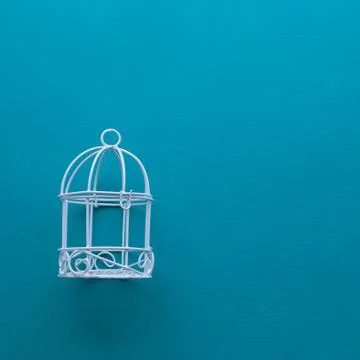 Small white decorative cage for interior decoration on a blue background. Stock Photos