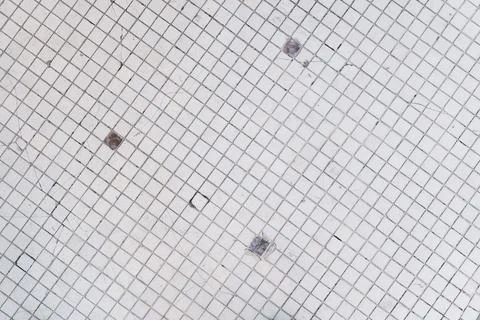 Small white dirty ceramic square tiles on the floor, outdoor, retro mosaic. Stock Photos