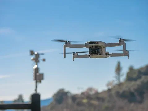 Small white drone with a built-in camera flies over a small weather station Stock Photos