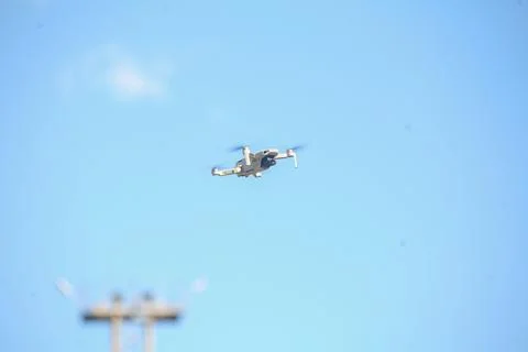 A small white drone flying high in a blue sky Stock-Fotos