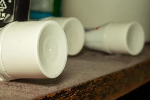 Small white empty plastic pots in a row on wooden surface Stockfoto's