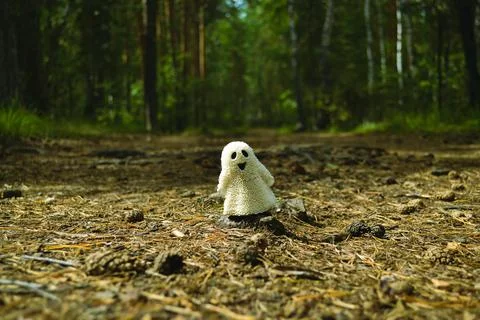 A small white ghost toy that smiles and stands on the ground in the forest Stock-Fotos