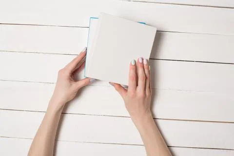 Small white half-open box in female hands. Top view. White table on the backg Foto stock