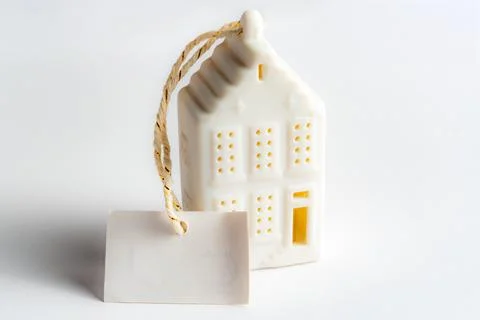 Small white house shape with a tag hanging shown on a plain background in a.. Stock Photos