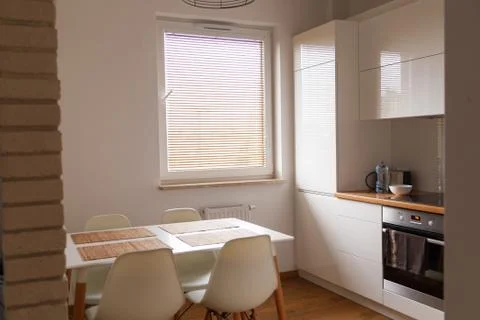 Small, white kitchen with table and new design chairs Stock Photos