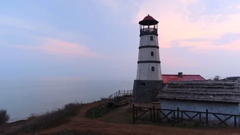 Small white lighthouse with a red top and a nearby boat along the seashore in th Stock-Footage 126881803