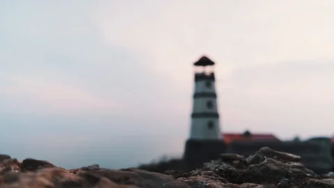 Small white lighthouse with a red top and a nearby boat along the seashore in th Stock Footage 126881821