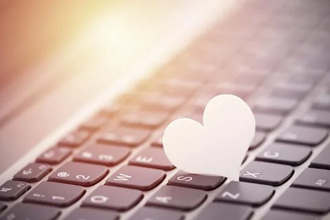 Small white paper heart on computer keyboard. Internet dating concept. Stock-Fotos