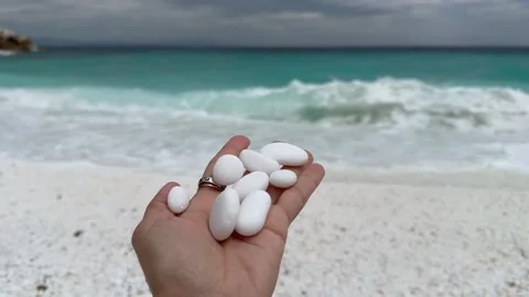Small white pebbles on a woman's palm. Marble Beach. Greece. Stock Footage 289740342