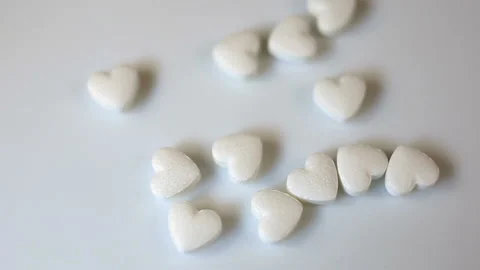 Small white pills in the shape of a heart move smoothly in the frame. Close-up, Stock Footage 145374551