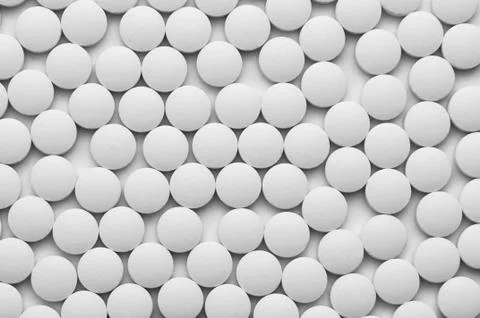 Small white pills on a white background close-up. Stock Photos