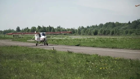 A small white plane is moving along the runway. The propeller is spinning Stock Footage 76608318