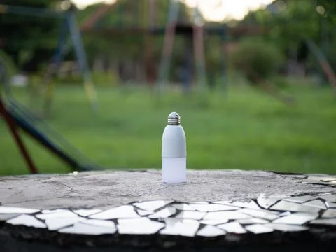 Small white plastic bottle on mosaic stone table outdoors Foto stock