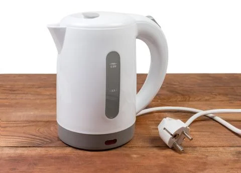Small white plastic electric kettle on an old wooden table Stock Photos