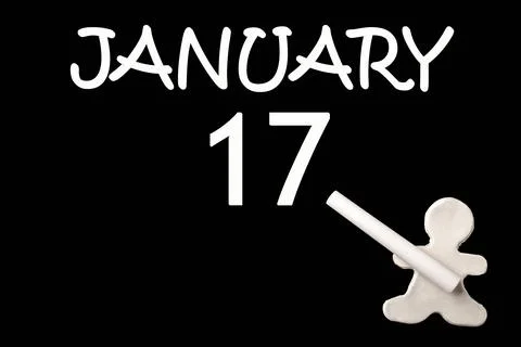 A small white plasticine man writing the date 17 January on a black board. Bu Stock Photos