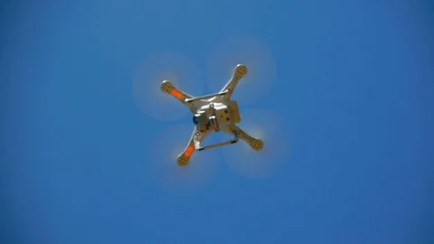 A small white quadrocopter, drone rises into a blue sky, a bottom view 스톡 동영상 76774058
