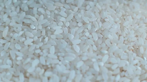 Small white rice grains are shown from four different angles on a light surface. Stock Footage 338297916
