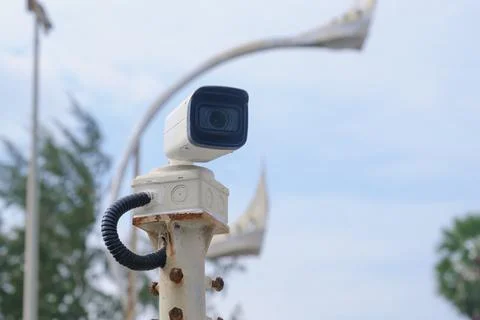 Small white road CCTV camera camera on a rusty pole along the road Stock Photos