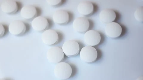 Small white round pills fly into the frame. On a white background, close-up, con Stock Footage 144643664