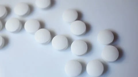 Small white round pills fly into the frame and are scooped up with a bare hand. Stock Footage 144643677
