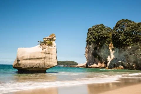 Small white sea stack off sandy beach in New Zealand. Stock Photos