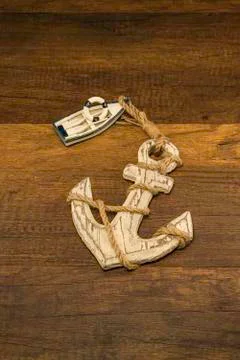 Small white ship with old large anchor on wooden background Foto stock