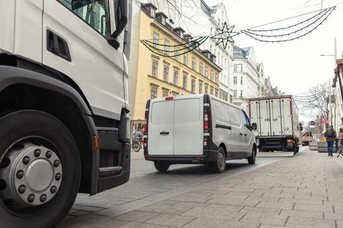 Small white van and mid size cargo truck parked for unloading at european old Stock-Fotos